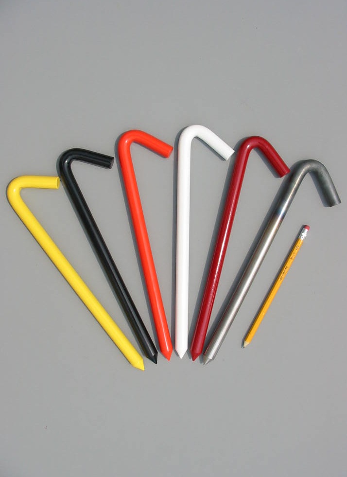 Twelve inch hook style tent stakes in six colors alongside a pencil for size comparison.