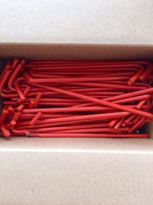 Box packed with 100 orange tarp stakes with lid open to view the stakes